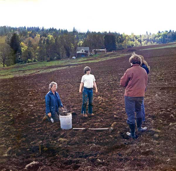 historical photo of people standing in a turned up farm field