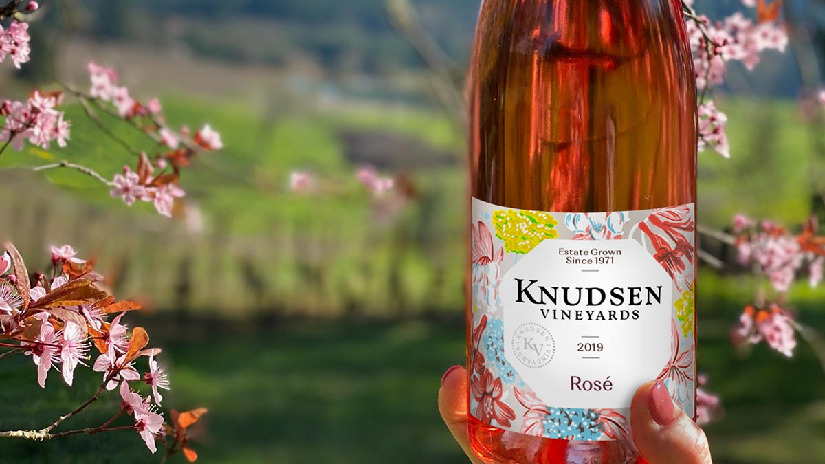 photo of a bottle of rose wine with a flowering tree in the distance