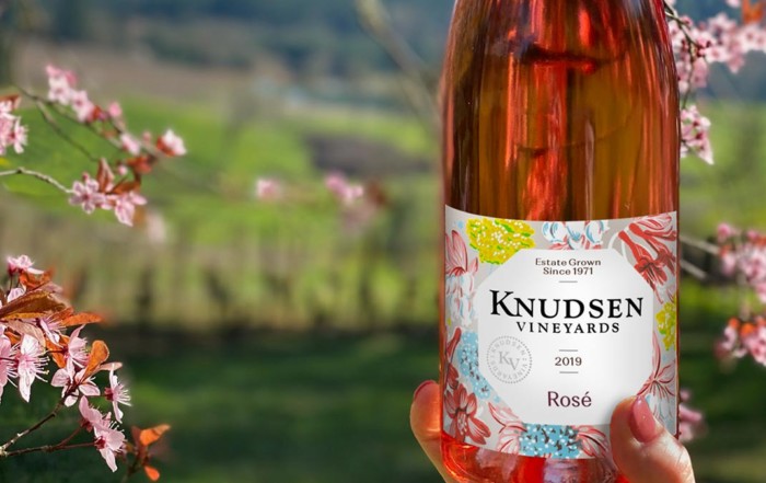 photo of a bottle of rose wine with a flowering tree in the distance