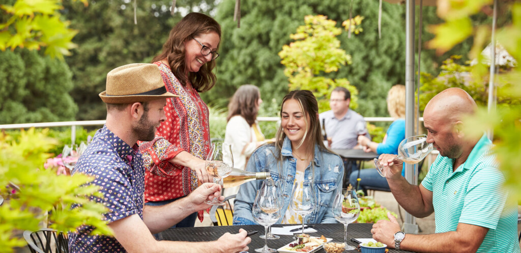 Happy guests receive a pour of rose wine from a smiling hostess.