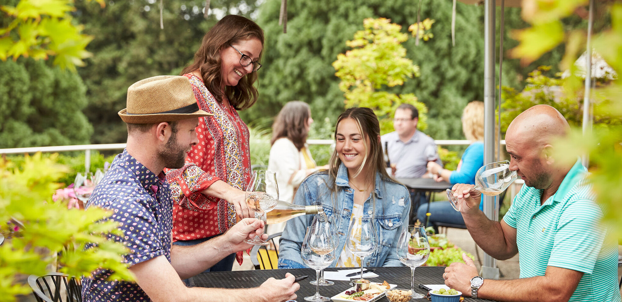 Outdoor wine tasting Happy guests receive a pour of rose wine from a smiling hostess.
