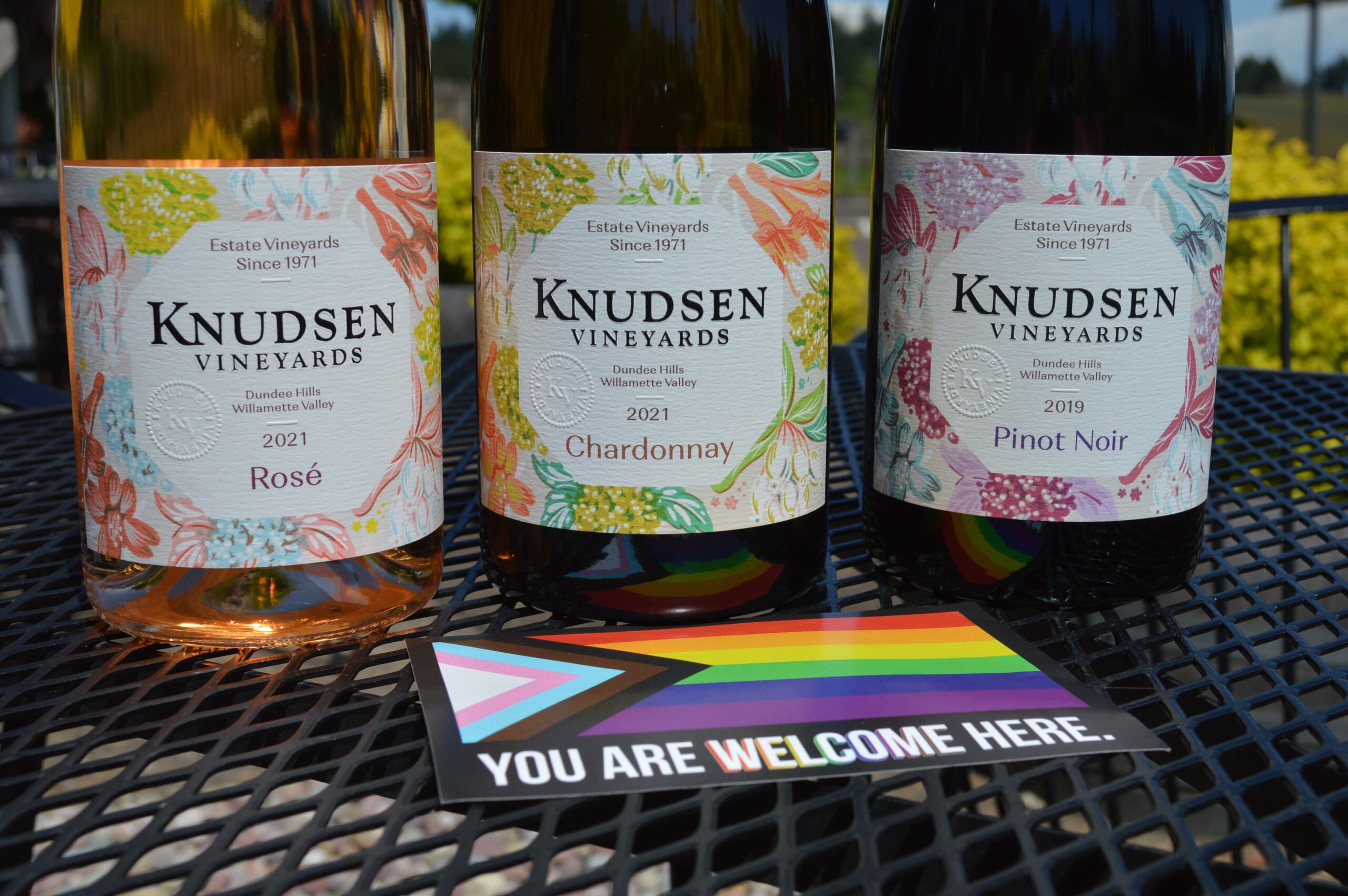 The Knudsen Vineyards Family Series lined up with a pride sticker that says "you are welcome here"